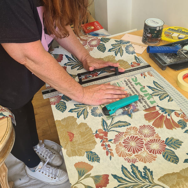 Workshop customer learning how to cut out wallpaper for decoupaging onto her furniture at a 1-to-1 Workshop in Stotfold.