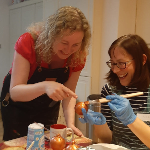 Michelle helping a Baubles and Bubbles party goer, advising how to apply the copper paint in thin layers at the bauble painting party