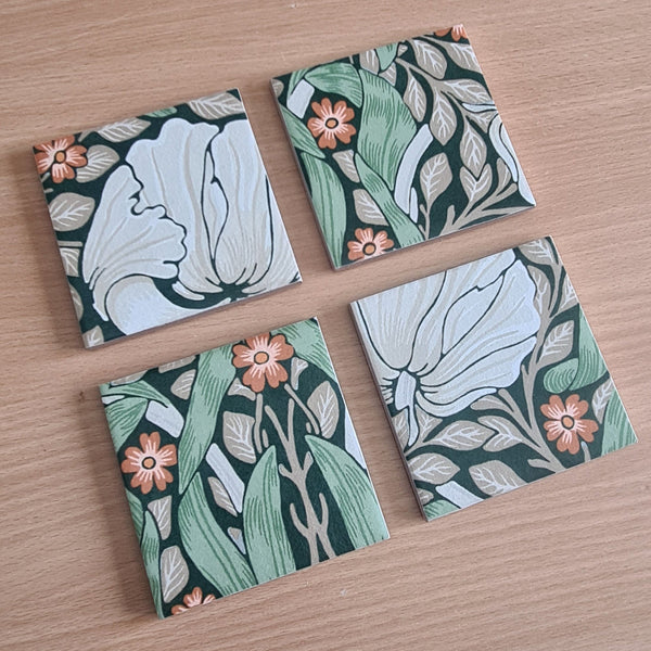 Close-up detail of handmade William Morris Pimpernel pattern ceramic coaster showing botanical floral design in green, cream and orange