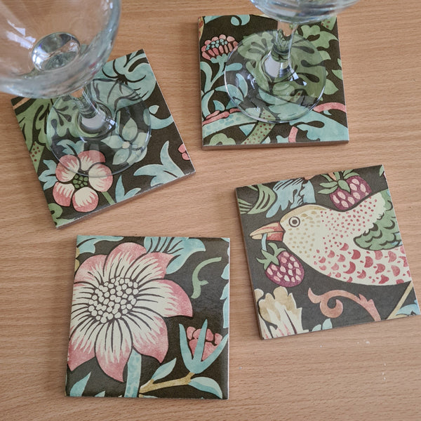 Handmade William Morris Strawberry Thief coaster set of 4 square ceramic coasters on coffee table with wine bottle and glasses