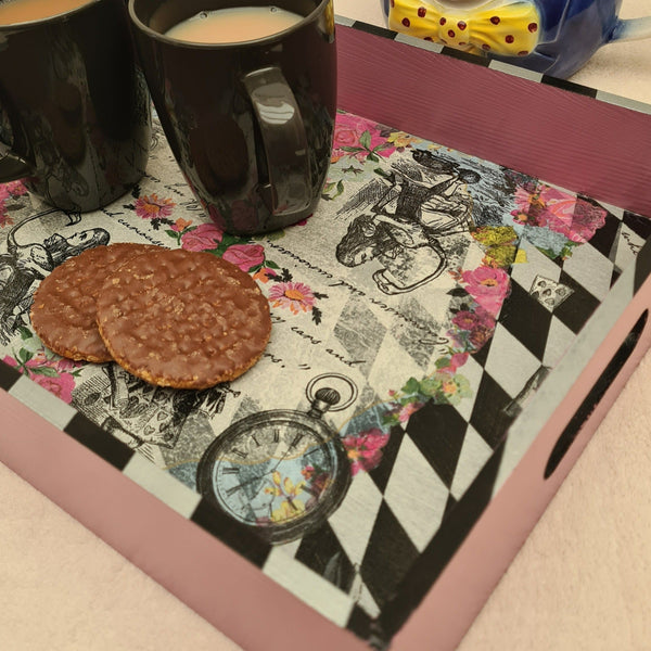 Angled view of handcrafted Alice in Wonderland serving tray with soft pink painted sides and harlequin detailing.