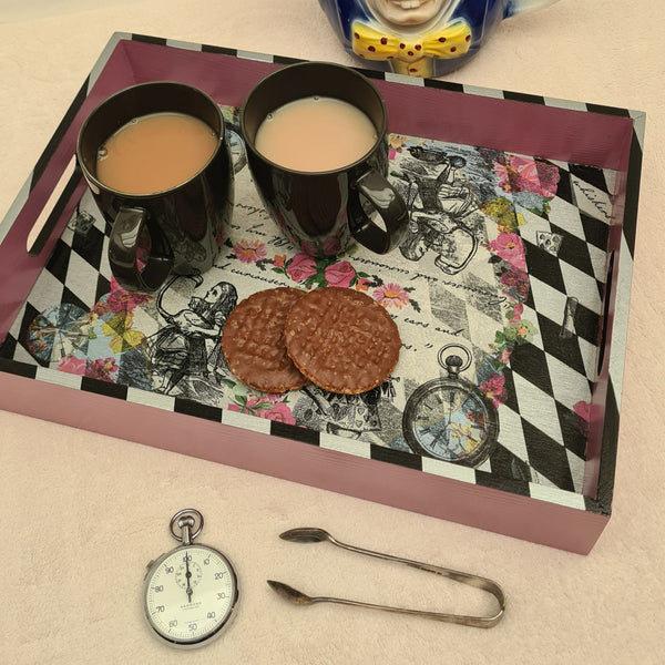 Handcrafted pink Alice in Wonderland wooden serving tray with black and metallic silver harlequin detailing, styled with tea and biscuits.