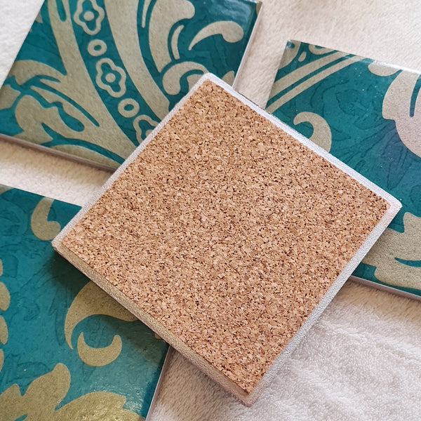 Reverse of a set of teal and champagne damask baroque-inspired matching coasters, stacked. 