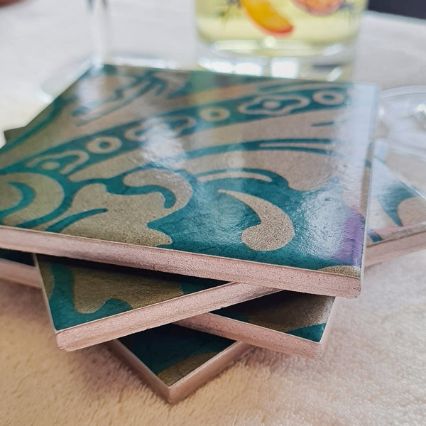 Set of teal and champagne damask baroque-inspired ceramic coasters, stacked with metallic edges.