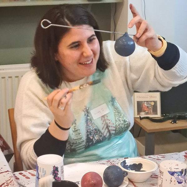 Baubles and Bubbles party goer painting the base coat on her ceramic baubles in Stotfold SG5.