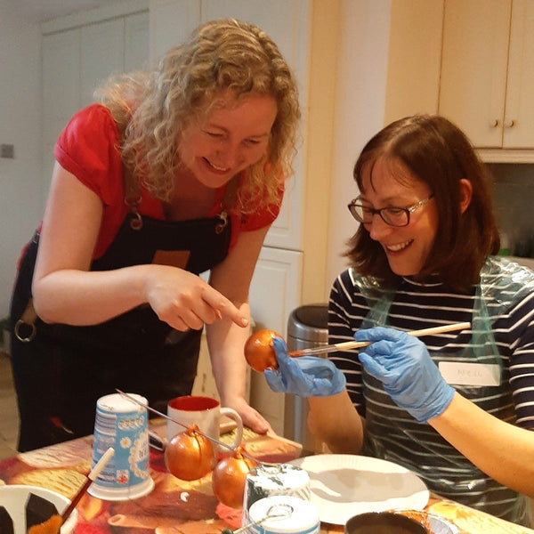 Michelle advising a Baubles & Bubbles party goer the best method to apply copper paint to her baubles.