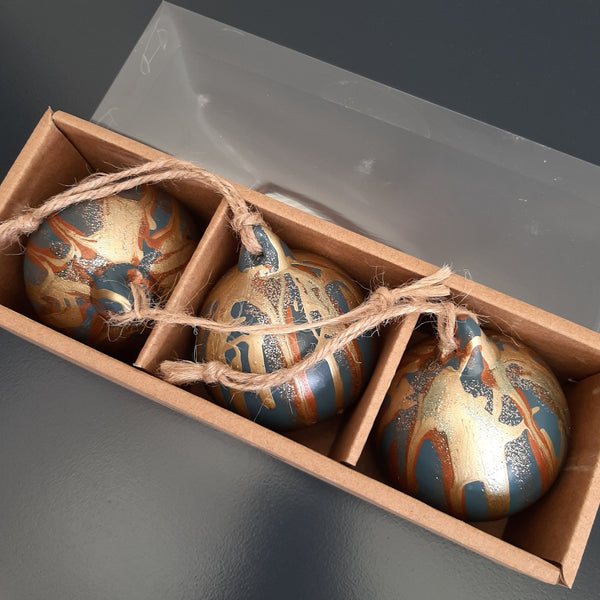 Three painted Christmas baubles in a storage gift box with twine, created at a Baubles and Bubbles party in Stotfold.