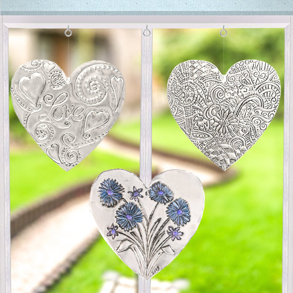 Personalised silver hanging heart created using a beginner-friendly metal embossing craft kit.