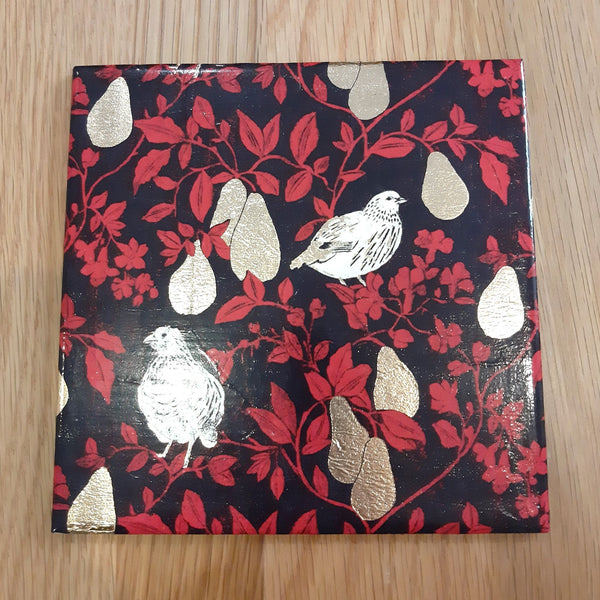 Handmade ceramic bottle mat featuring a festive Partridge in a Pear Tree design with gold foil detail.