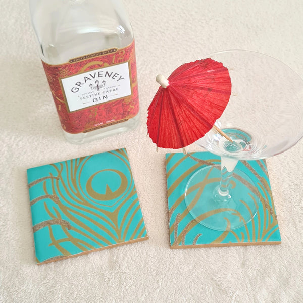 Teal Peacock Feather ceramic coasters styled with a gin bottle and cocktail glass.