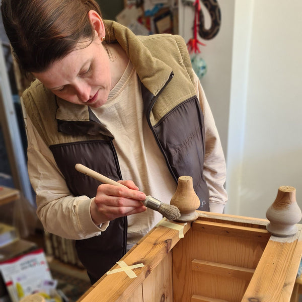 A lady learning to paint wooden furniture during a private 1-to-1 workshop at The Furniture Bureau.