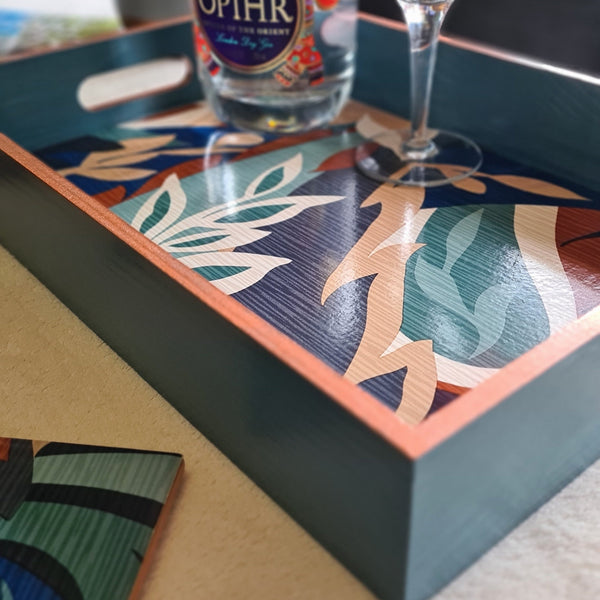 Angled view of bold colourful retro leaf design on a handcrafted deep teal wooden serving tray.