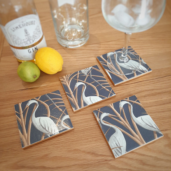 Handmade Chateau Nouveau Heron ceramic coasters styled on a coffee table as totally unique tableware with a bottle and glass.