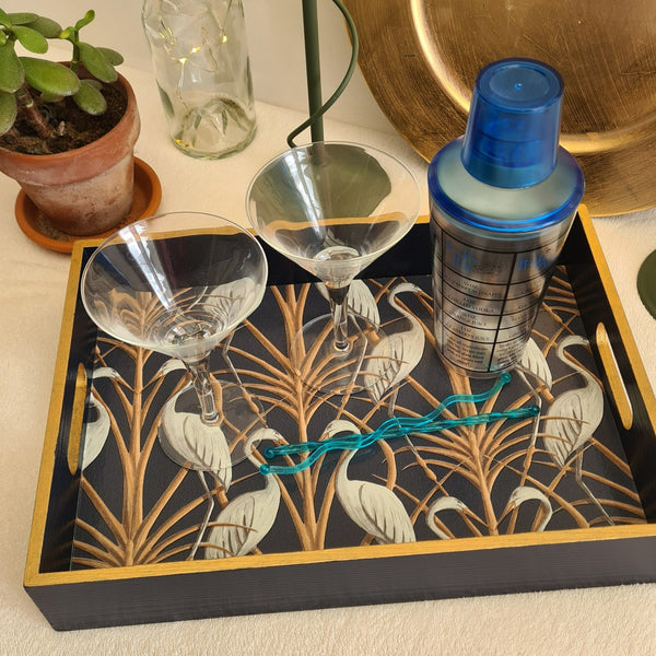 Nouveau Heron serving tray styled with cocktail glasses, featuring navy blue paint and metallic bronze edging.