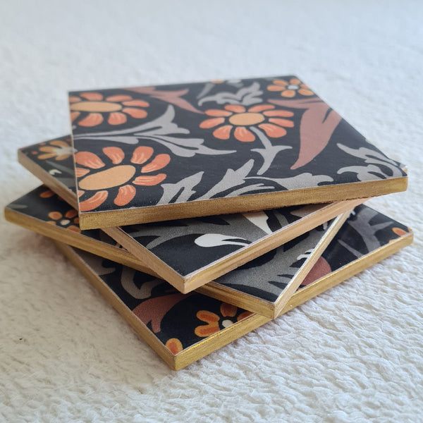 Stacked Set of four handmade William Morris Blackthorn ceramic coasters in the Charcoal Grey colourway, with metallic edging.