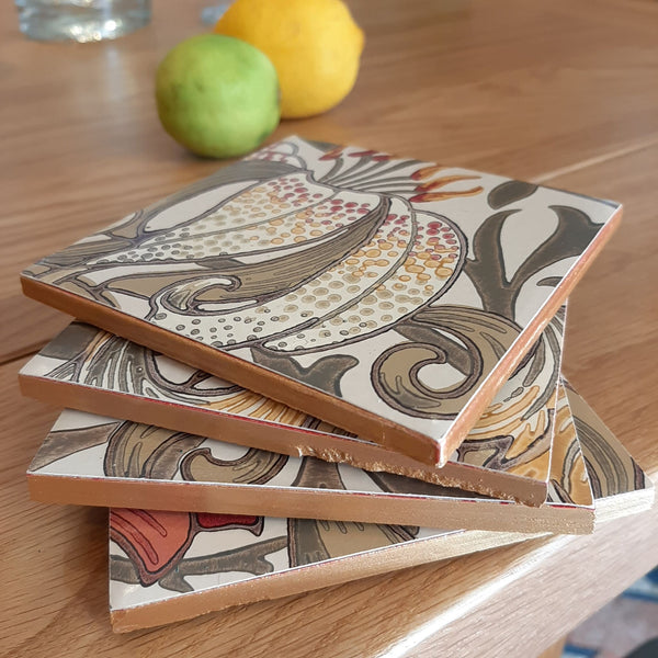 Stacked William Morris Golden Lily ceramic coasters in Biscuit showing the hand-painted metallic edging.