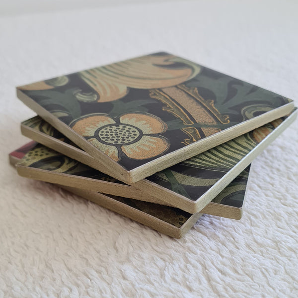 Stacked set of four handmade William Morris Golden Lily ceramic coasters in the Grey colourway showing metallic edges.
