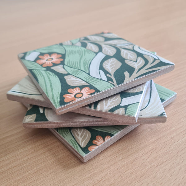 Close-up of champagne metallic edging on a stack of handmade William Morris Pimpernel ceramic coasters.