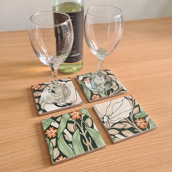 William Morris Pimpernel handmade ceramic coasters styled with wine glasses on a coffee table.