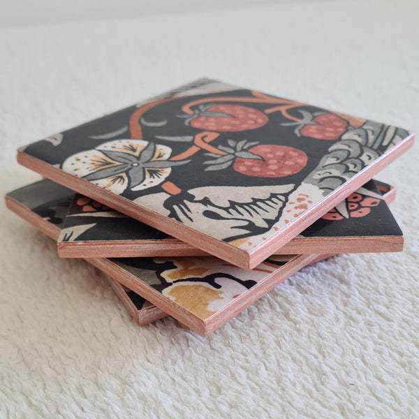 Handmade William Morris Strawberry Thief ceramic coasters in the Charcoal Grey colourway styled stacked showing metallic edging.
