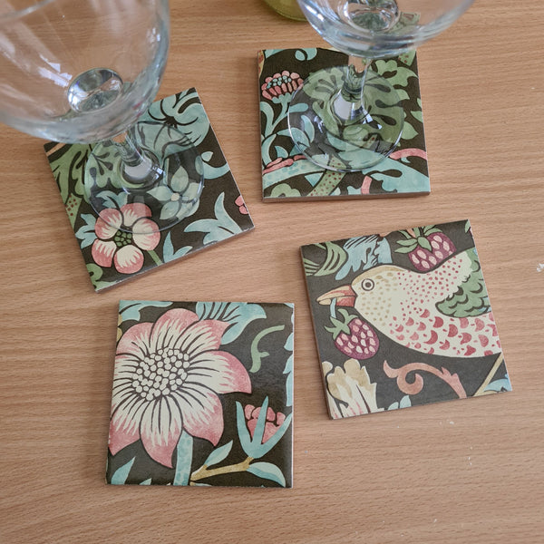 Handmade William Morris Strawberry Thief ceramic coasters in the warm Chocolate Brown colourway styled with glasses on a coffee table.