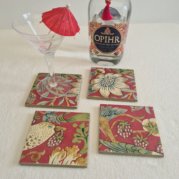 Handmade William Morris Strawberry Thief ceramic coasters in the Crimson Red colourway styled with a bottle and glass.