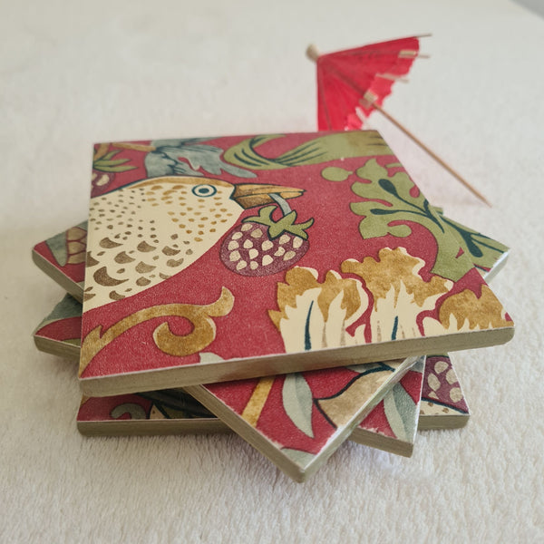 Close-up of strawberries, flowers and foliage on a handmade William Morris Strawberry Thief Crimson Red coaster.
