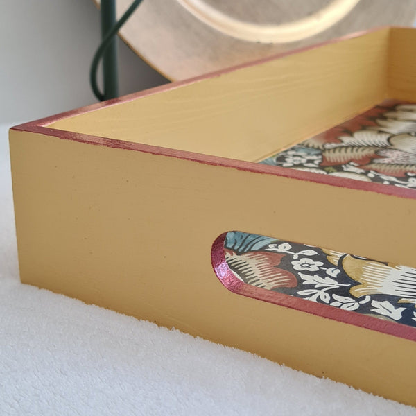 Mustard yellow William Morris Wandle wooden serving tray with integrated handles and rusty red metallic edging.