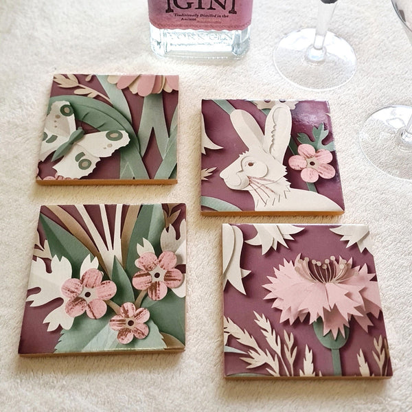 Set of four handmade Woodland ceramic coasters featuring hares, birds, butterflies and flowers in a 3D-style design.