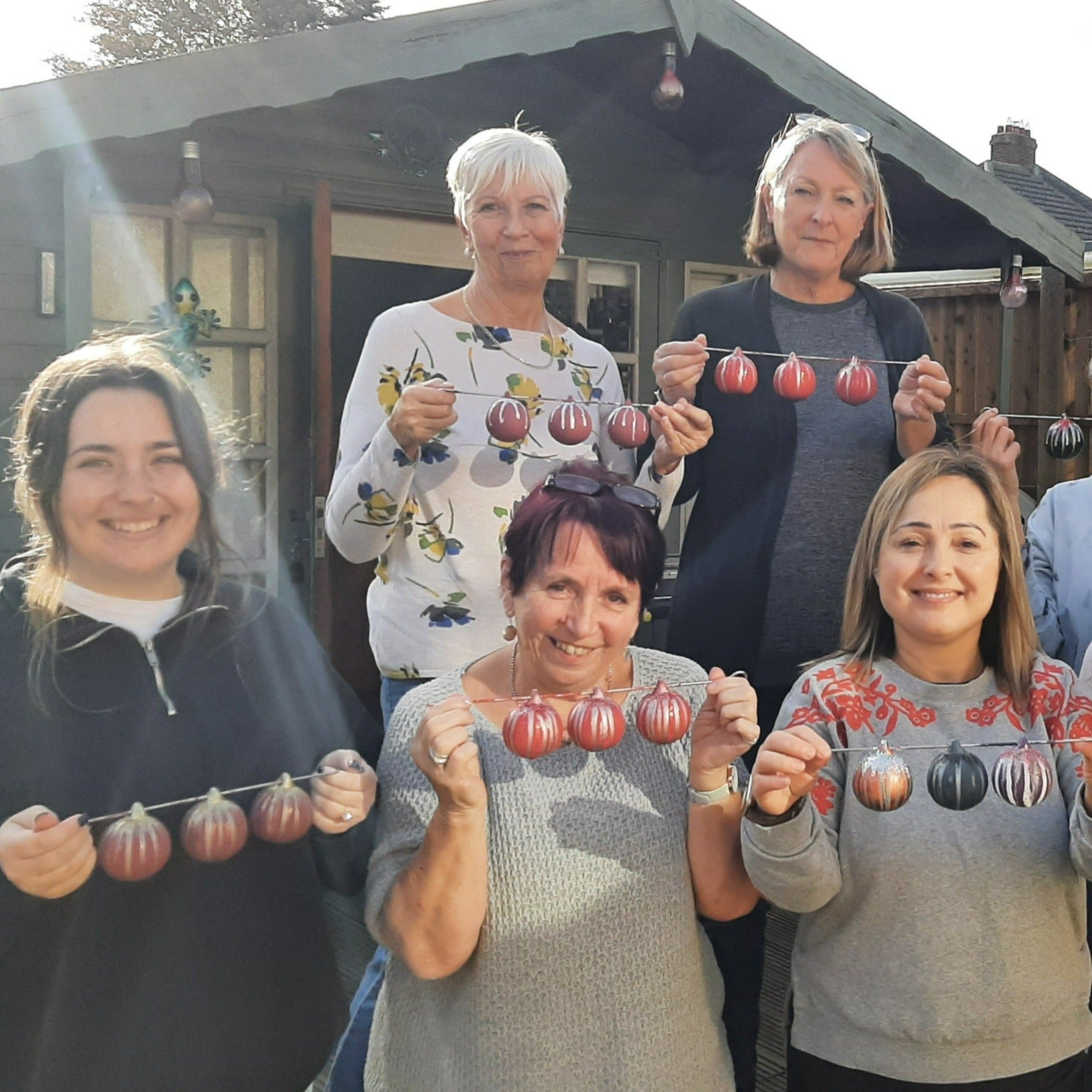 Ladies showing off their hand painted baubles at a Baubles and Bubbles bauble paint party in Stotfold